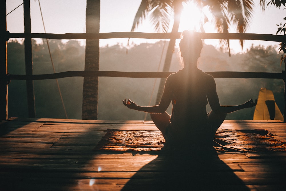 Silhueta em posição de meditação, em contraluz dourado, num espaço tranquilo ao entardecer.